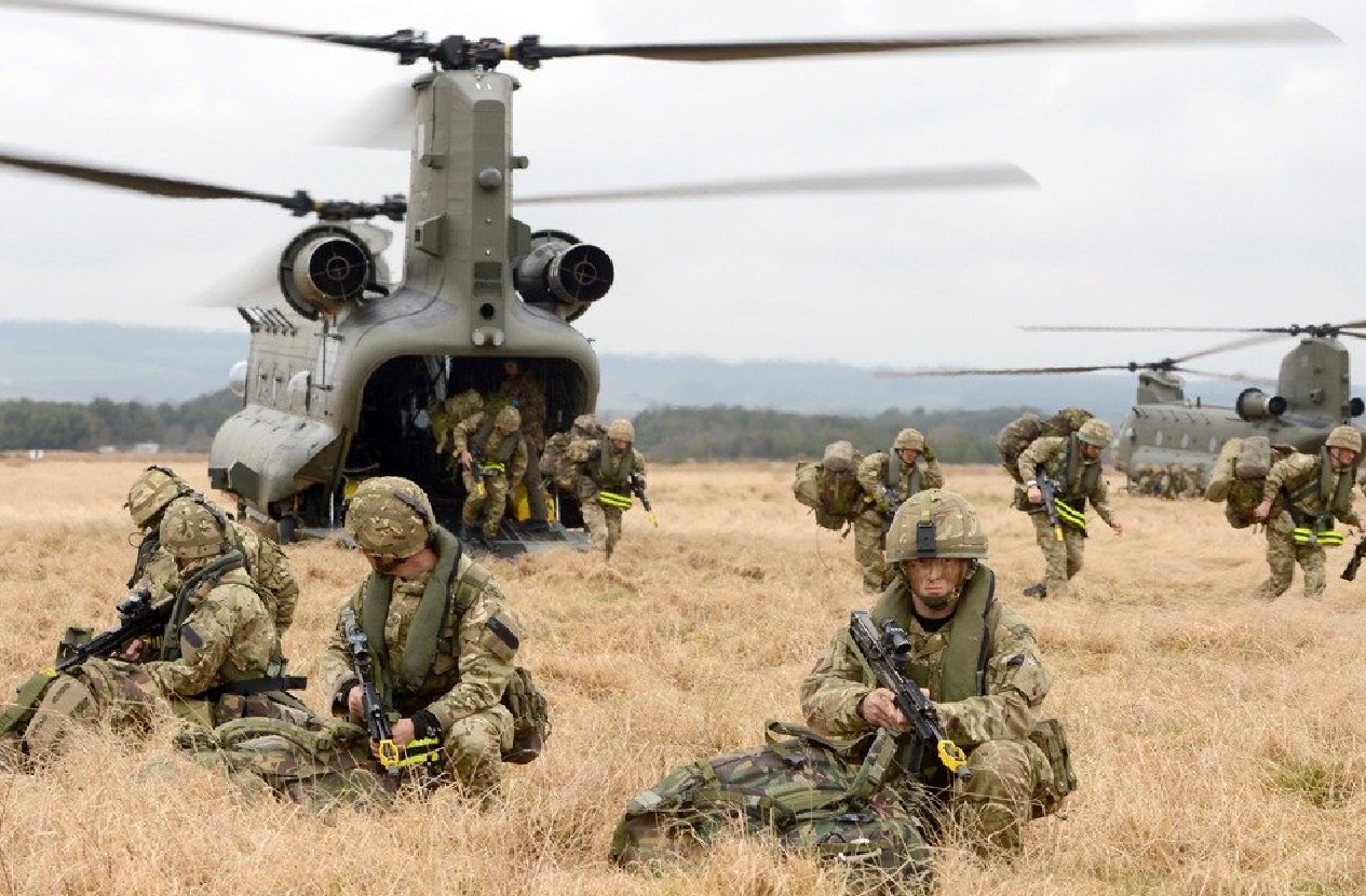Migration Watch Newsletter image of British troops and a helicopter in a field training.